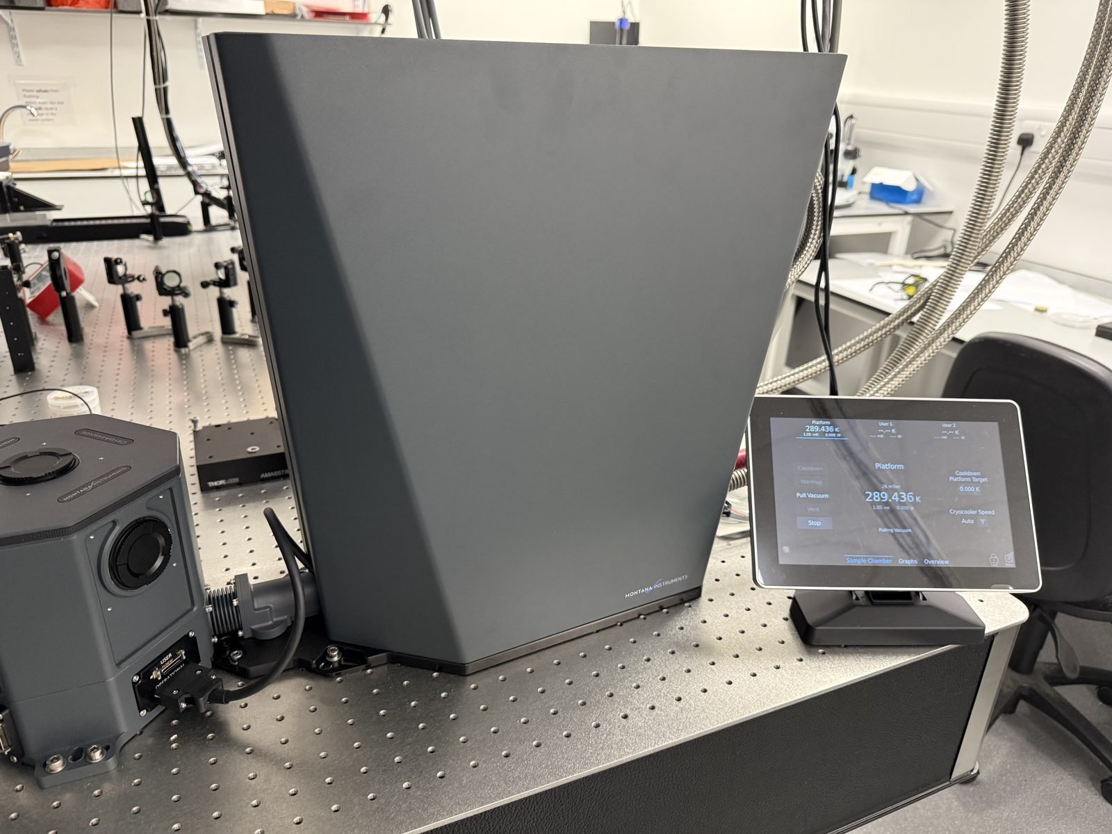 Montana Instruments CryoAdvance 100 optical cryostat on the optical table, with its sample chamber and touchscreen controller